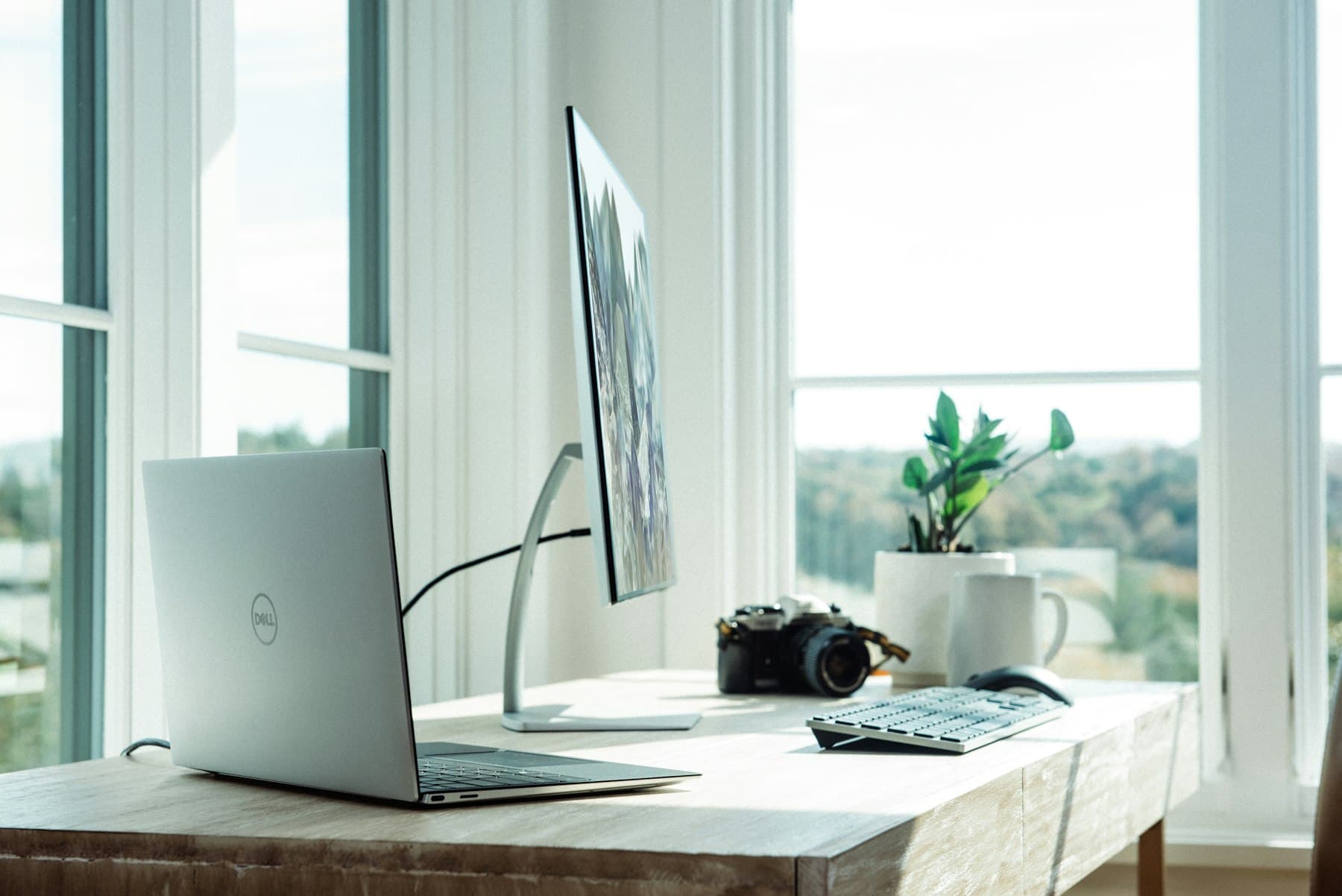 A bright home office desk with a laptop beside a window